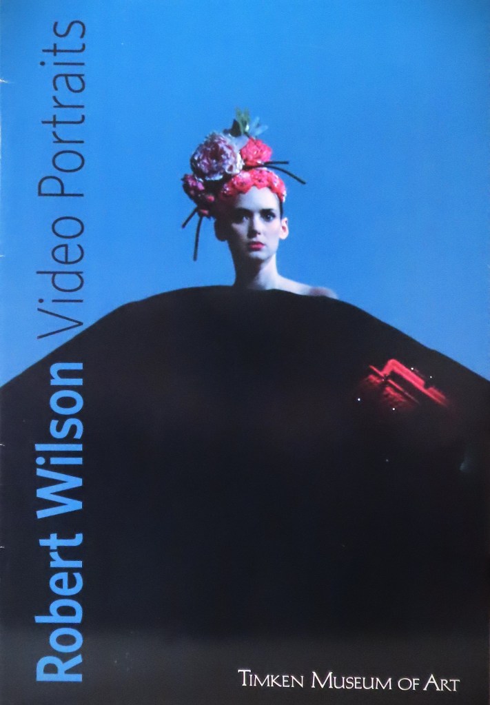 Winona Ryder is on the cover of this art catalog, a still from her video portrait with artist Robert Wilson. On her head is an ornate headress of real flowers composed. Winona isn't smiling. Her shoulder peeks out behind a swath of black.